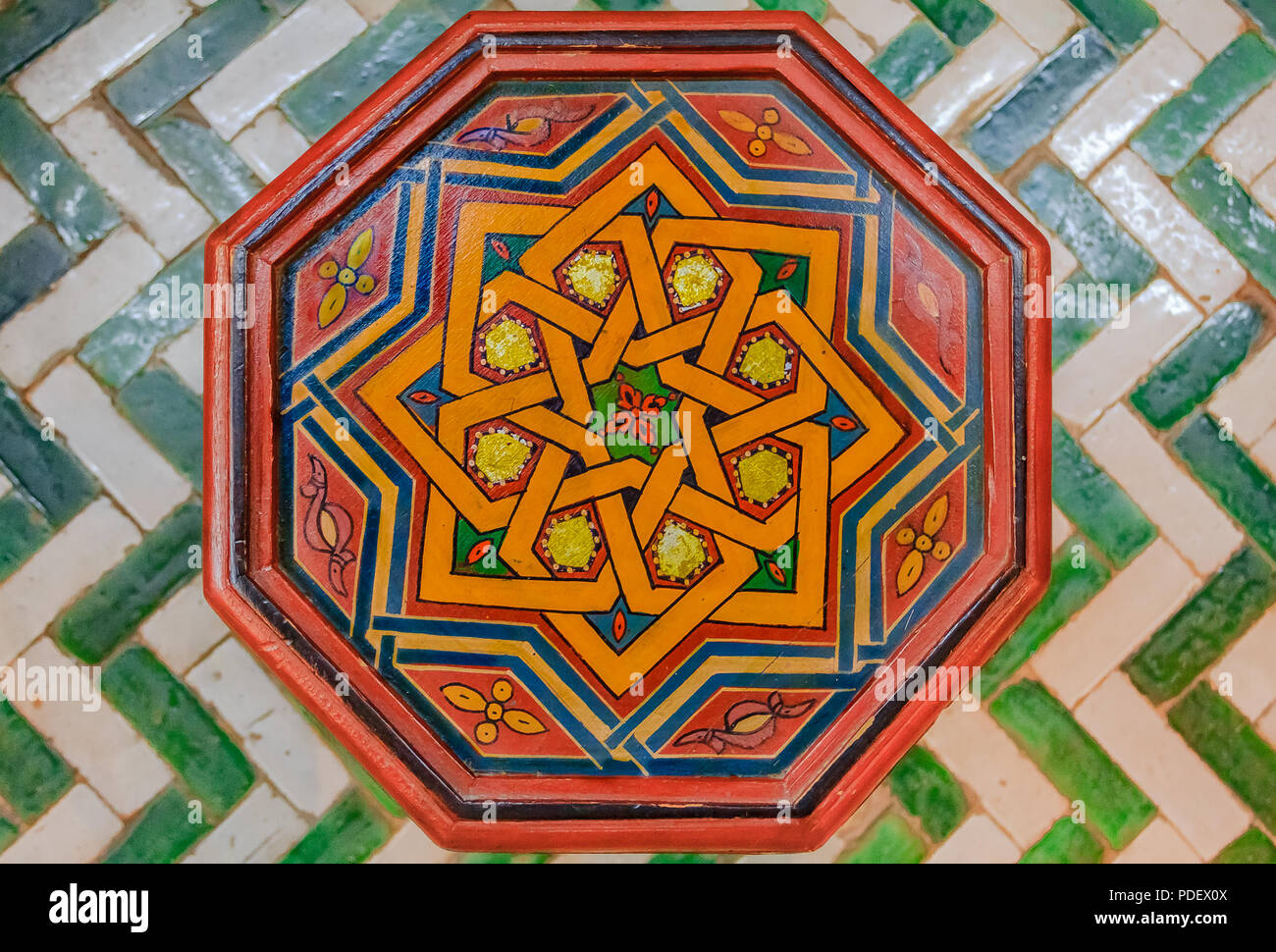 Peinte à la main décoré tabouret marocain traditionnel avec des dessins géométriques, debout sur un plancher de tuiles Banque D'Images