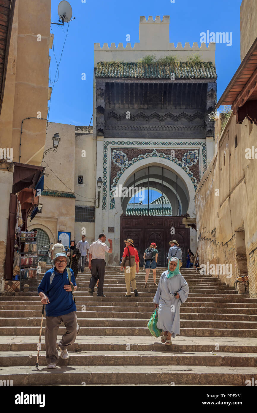 Fes, Maroc - 11 mai 2013 : les habitants et les touristes se promener dans la médina de Fès, sur les étapes menant à une porte ouvragée décorée de mosaïques Banque D'Images