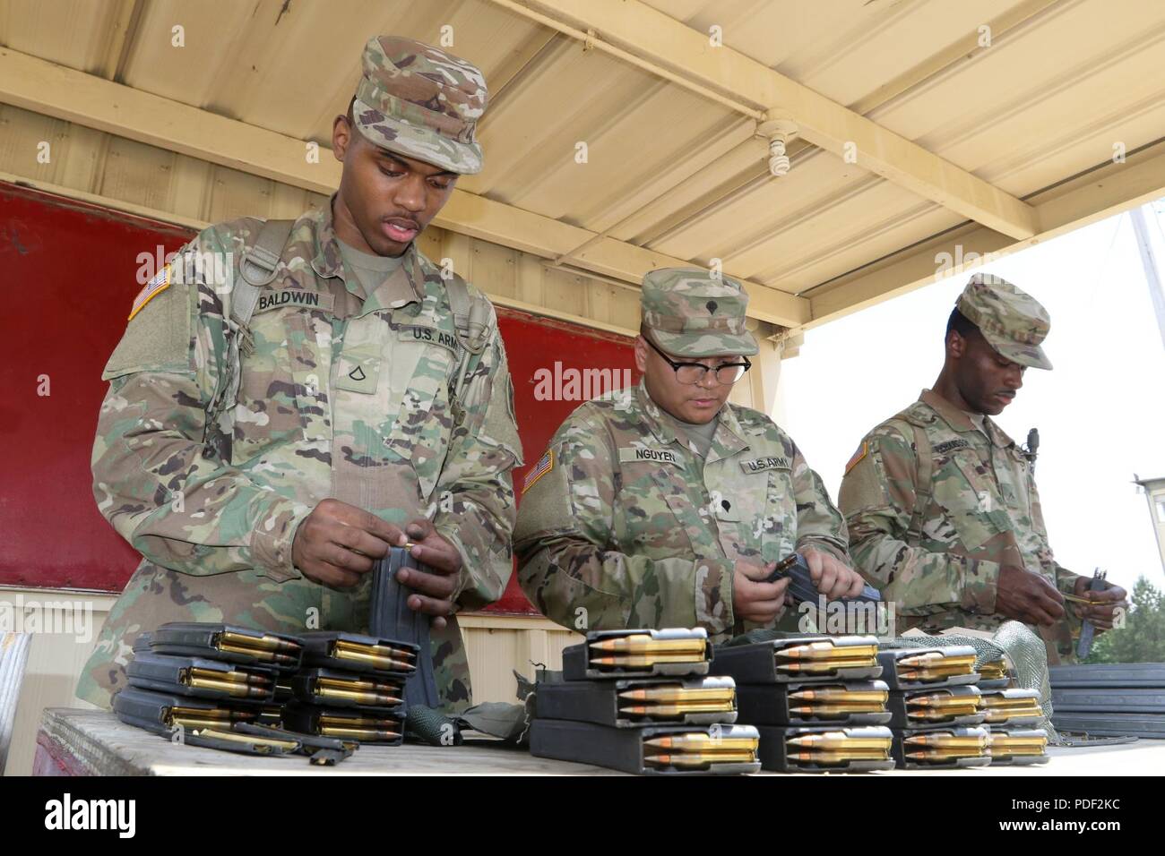 De gauche à droite, le circuit de l'armée américaine. Nieko D. Baldwin de Snellville, Ga, SPC. Steven Nguyen de Decatur, Géorgie, et Pvt. Charles E. Richardson de Decatur, Géorgie, avec le 642e Groupe de soutien régional charger des magazines pour l'épreuve de qualification au tir de l'unité à Fort Benning 18 mai. Banque D'Images