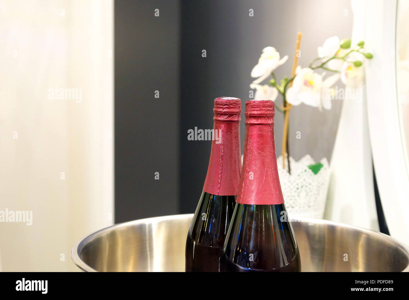 Bouteilles de vin rouge sur la glace dans un récipient en verre. À côté des  fleurs sur le miroir arrière-plan. Définition de mariage Photo Stock - Alamy
