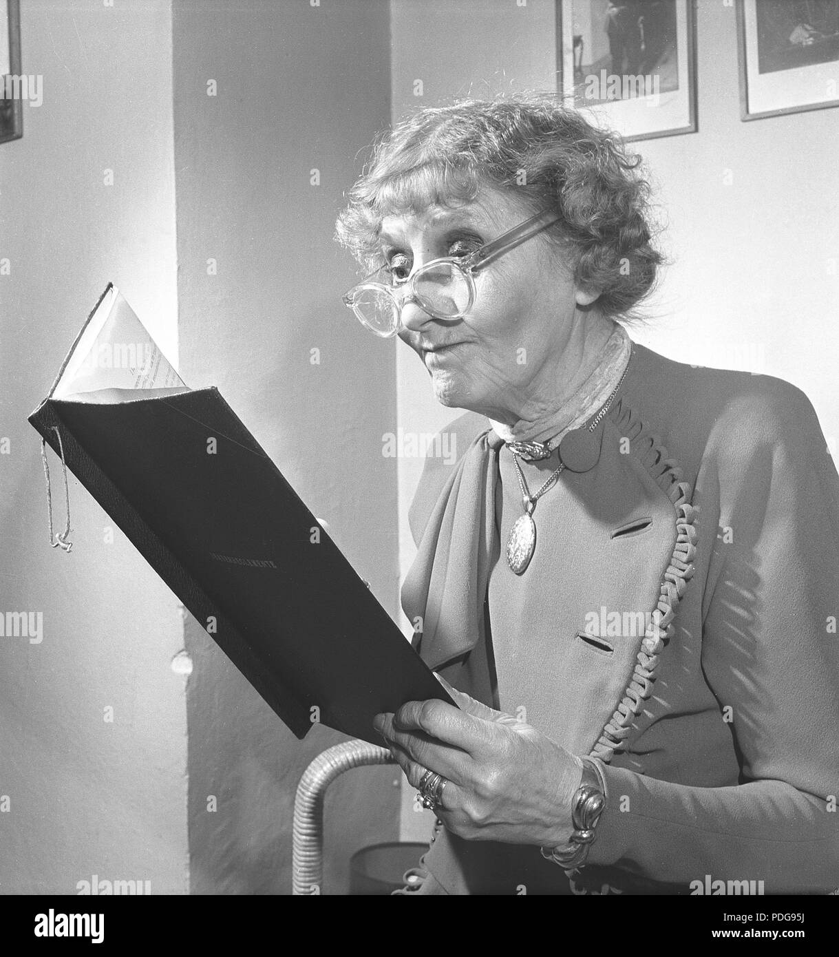 1950s femme avec lunettes. Une dame âgée avec ses lunettes sur le bout de son nez, est en train de lire un document. Suède 1950 photo Kristoffersson/AX40-4 Banque D'Images