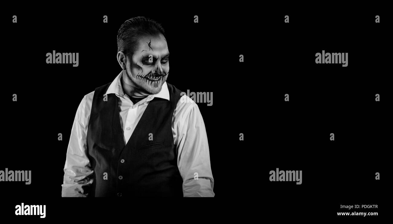 Portrait d'un homme bien habillé avec tête de maquillage. L'horreur et le thème de l'Halloween, tourné avec l'éclairage de théâtre et d'effets. Image en noir et blanc Banque D'Images