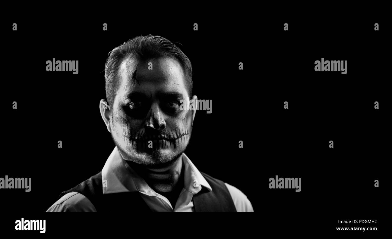 Portrait d'un homme bien habillé avec tête de maquillage. L'horreur et le thème de l'Halloween, tourné avec l'éclairage de théâtre et d'effets. Image en noir et blanc Banque D'Images
