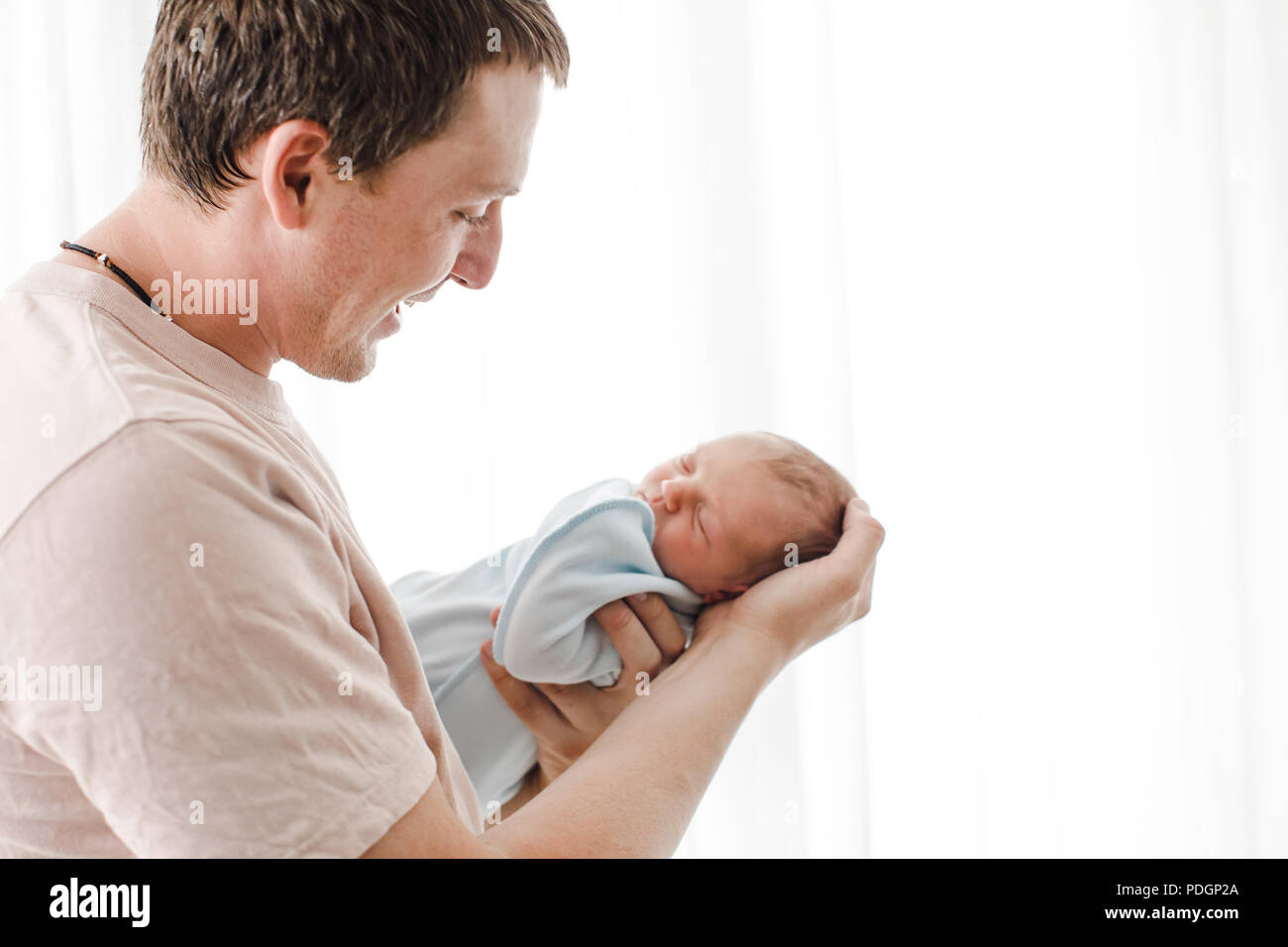 Père attentif à l'enfant nouveau-né sur les mains Banque D'Images