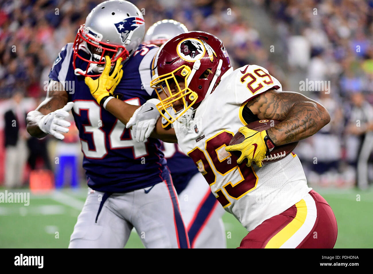 Foxborough, USA. 9 août 2018 : Redskins de Washington d'utiliser de nouveau Derrius Guice (29) New England Patriots bras rigide arrière défensif J.C. Jackson (34) lorsqu'il se déplace le ballon sur le terrain pendant la pré-saison NFL match de football entre les Redskins de Washington et les New England Patriots au Stade Gillette, à Foxborough, Massachusetts. La défaite des patriotes les Redskins 26-17. Eric Canha/CSM Banque D'Images