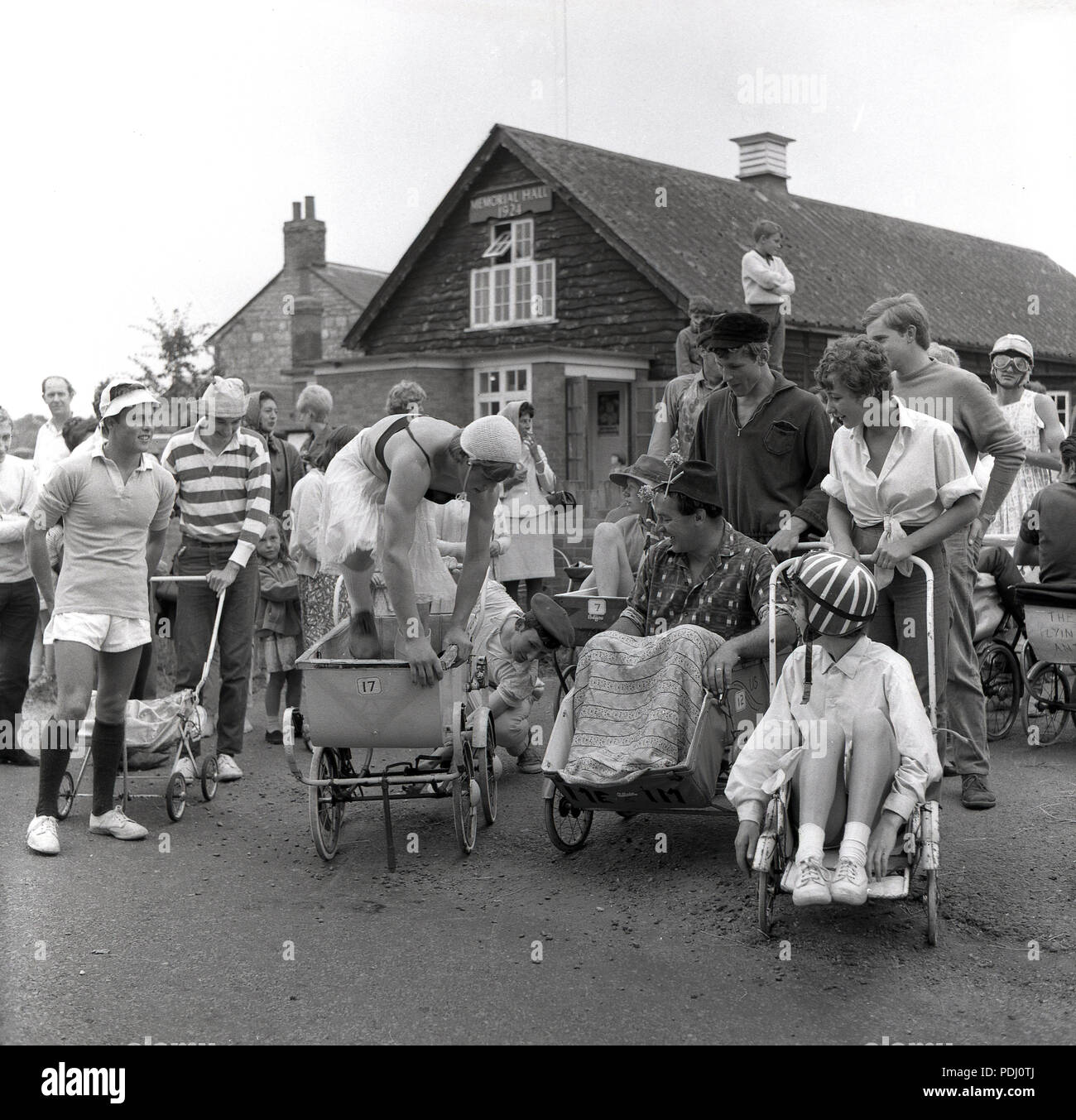 Années 1960, des concurrents dans le landau dans le village course chairtty  fete rassembler en dehors de la salle des fêtes pour le début de  l'événement, England, UK Photo Stock - Alamy