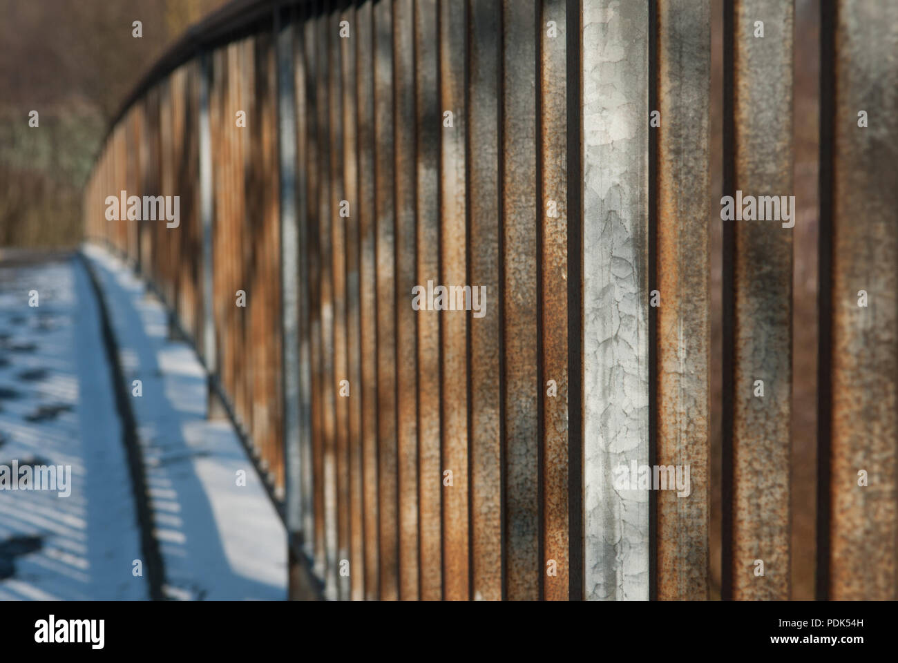 Métal rouillé, garde-corps du pont couvert de neige éclairé par le soleil du matin Banque D'Images