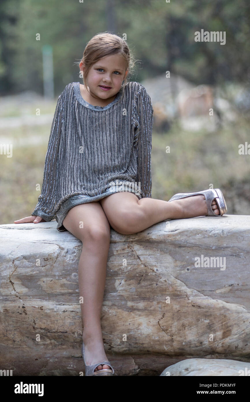 Charmante fille, en robe haute couture, posant sur de gros rocher avec rose  dans sa main. Smiling at camera avec deux dents en moins. La verticale et  mo Photo Stock - Alamy