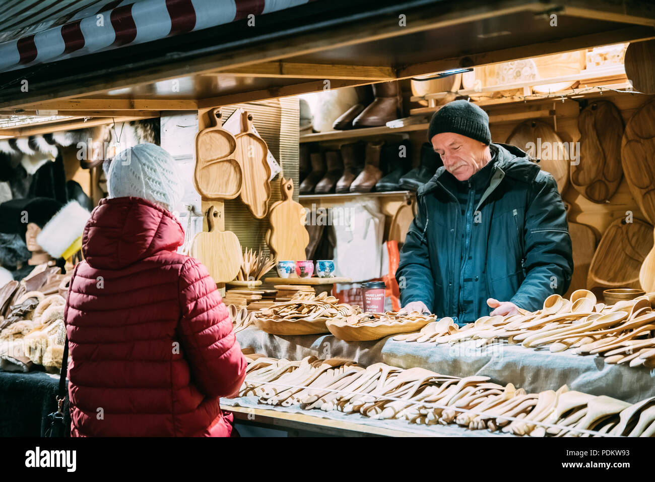 Riga, Lettonie - le 18 décembre 2017 : Old Man vendeur vend divers en bois naturel d'artisanat sur le marché de Noël de l'hiver. Pays baltes de souvenirs populaires Banque D'Images