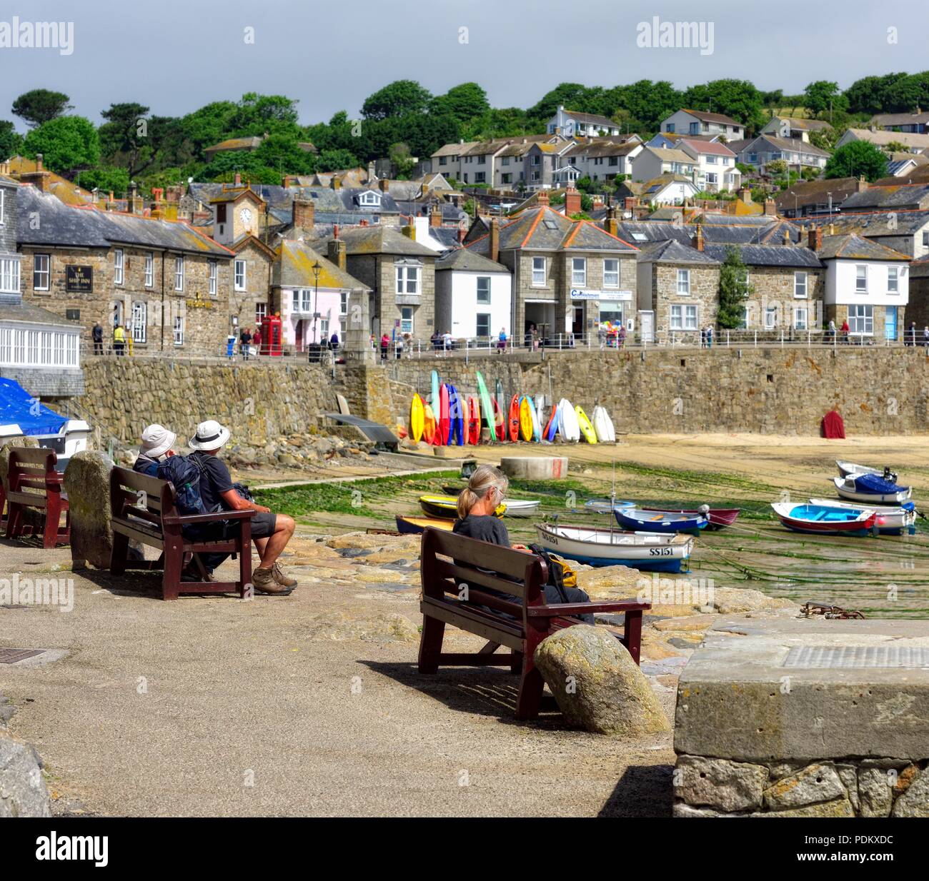 Des gens assis sur un banc dans le port Mousehole, Cornwall, Angleterre, Royaume-Uni Banque D'Images