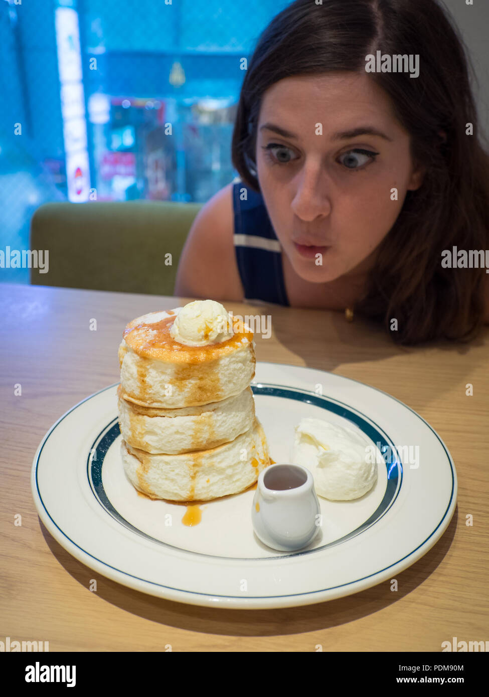 Une jolie petite fille brune est excitée par des crêpes japonaises moelleuses à soufflé de qualité supérieure de Gram Cafe & Pancakes à Hiroshima, au Japon. Banque D'Images