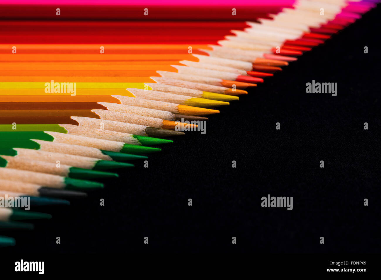 Une macro image d'une ligne diagonale de crayon de couleur conseils affûtés avec beaucoup d'espace négatif noir pour copie. La ligne est très ordonné et établi Banque D'Images