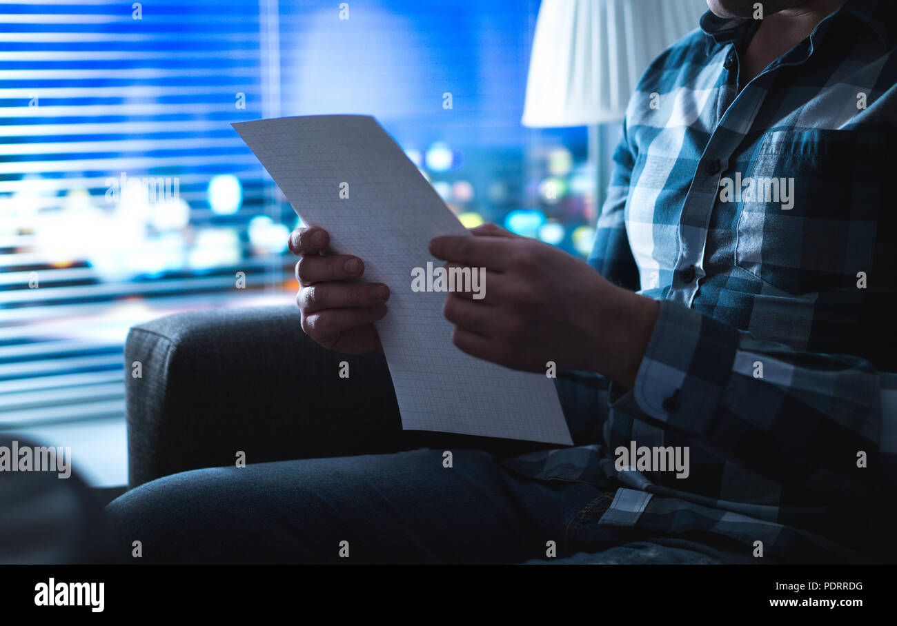 La lecture de l'homme lettre dans le noir la nuit. Personne écrit remarque dans l'ombre accueil par la fenêtre. Inspiration soudaine ou de mauvaises nouvelles. Banque D'Images