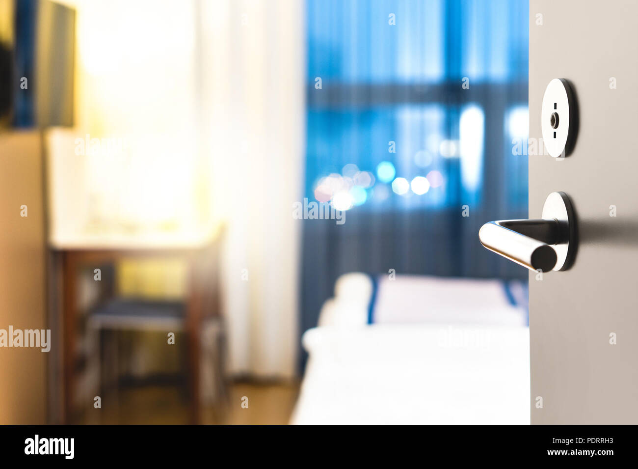 Chambre d'hôtel porte ouverte. Service d'hébergement propre et élégant. Close up de poignée. Lit, table pour les repas et tv. Déplacement, d'hébergement et de motel concept. Banque D'Images