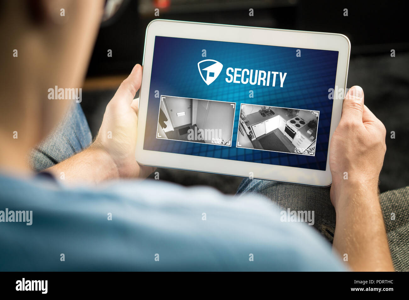 L'homme à l'aide de système de sécurité de la maison et de l'application en tablette. Regarder en direct à l'intérieur de l'appareil photo de la protection d'une maison ou d'appartement. Banque D'Images