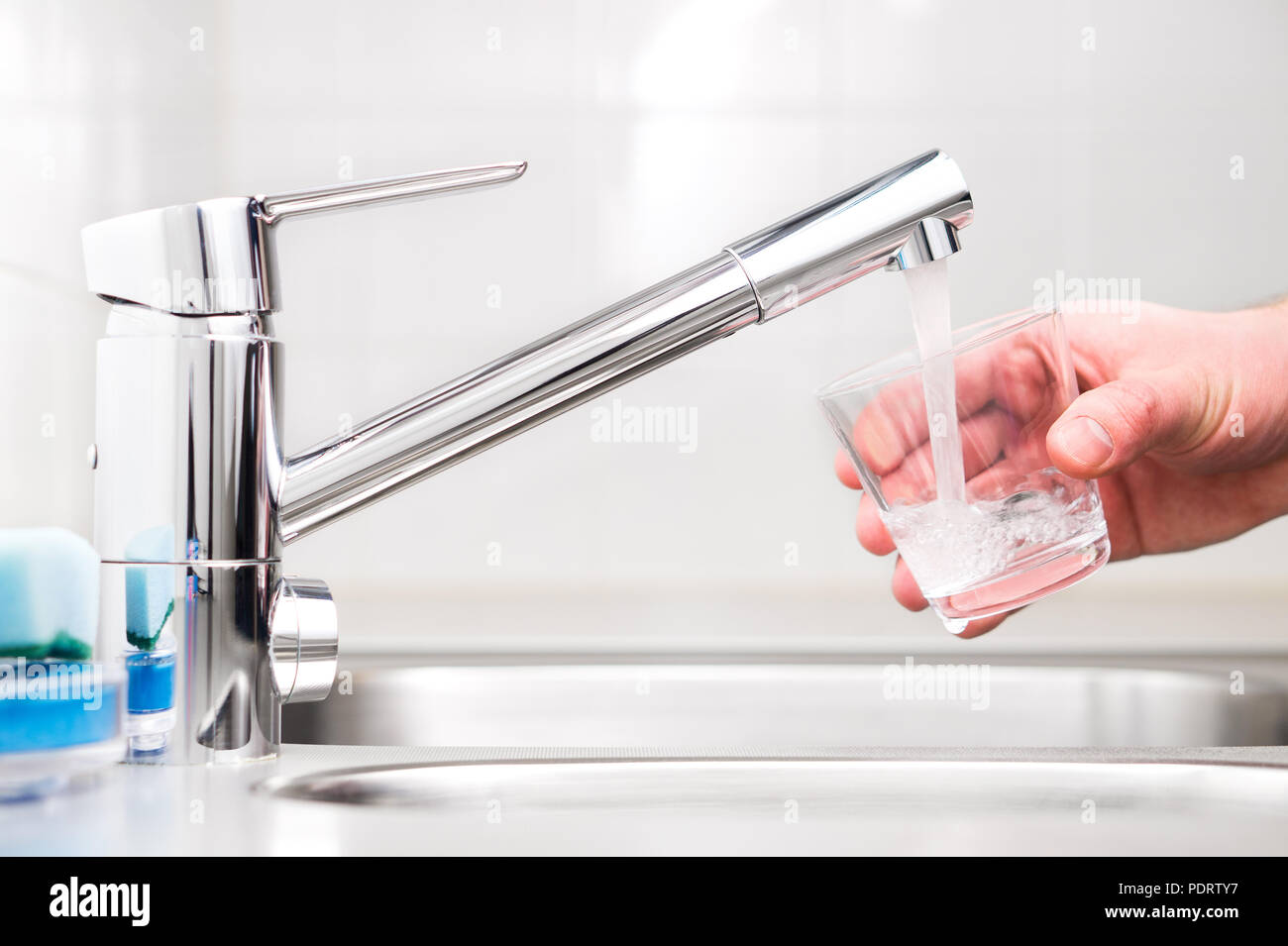 Verre de remplissage avec l'eau du robinet. Robinet moderne et d'un évier de cuisine à domicile. Man pouring fresh boire à la tasse. Banque D'Images