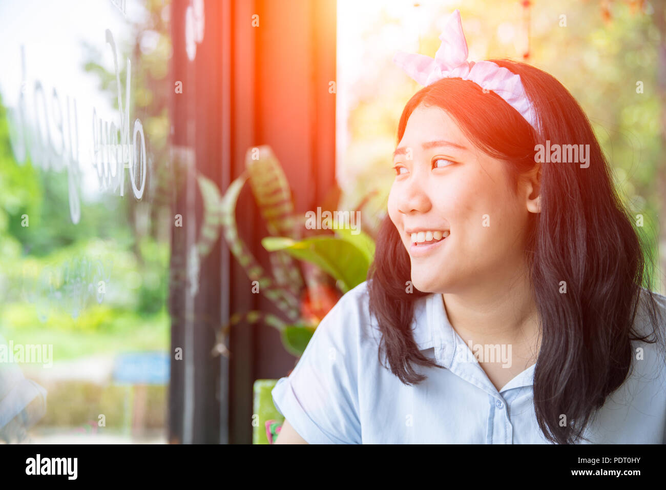 Cute Asian chubby gras dodu jeune adolescente sourire à Windows Banque D'Images