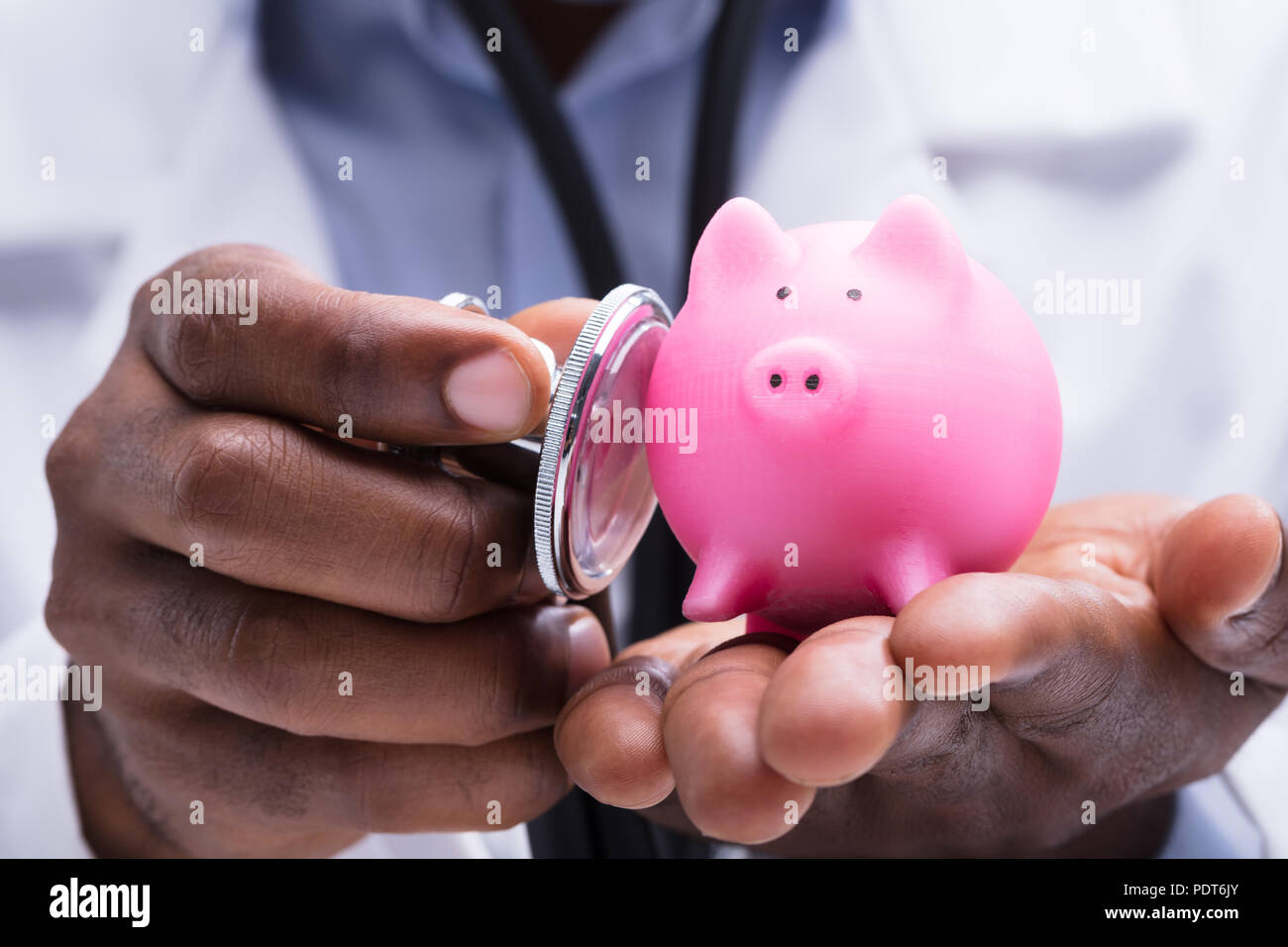 Close-up of a doctor Pink Piggybank miniature dans sa main avec stéthoscope Banque D'Images