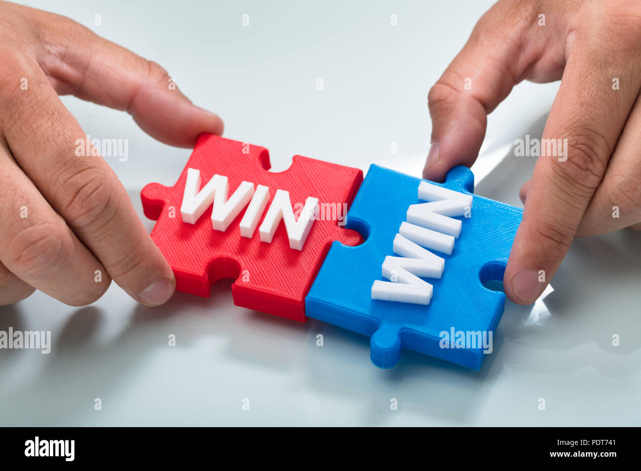 Close-up of a person's hand reliant deux bleu et rouge win word puzzle Banque D'Images