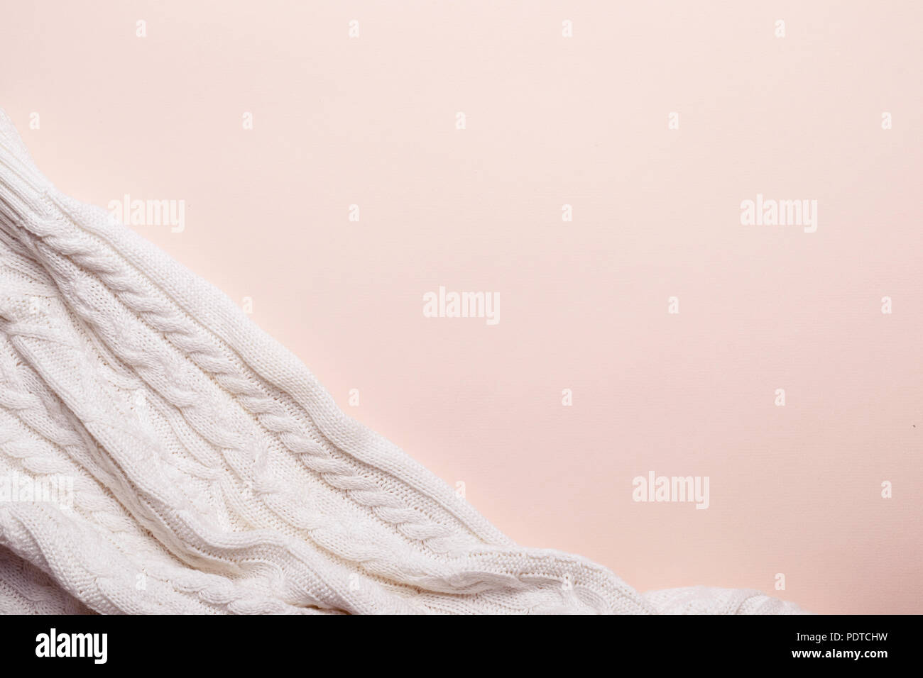 Plaid doux tricoté blanc sur fond rose. romantique chaude prendre soin concept. Banque D'Images