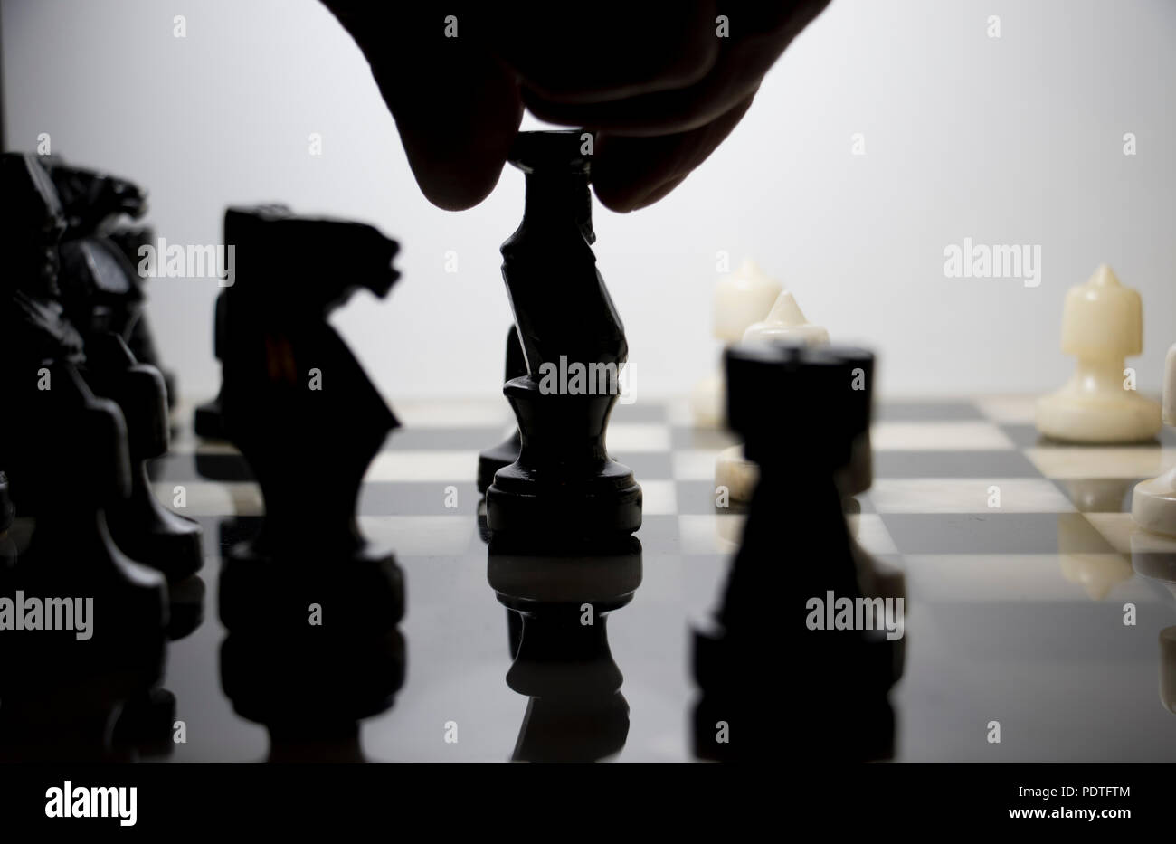 La Reine noire est déplacé dans un jeu d'échecs. Silhouette de pièces d'échecs sur un échiquier de marbre. Banque D'Images