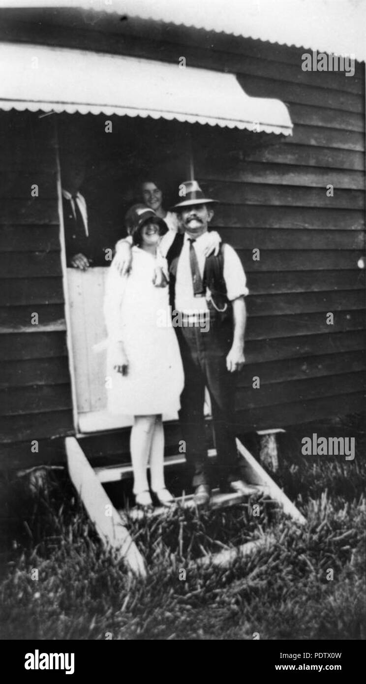 211 119988 StateLibQld 1 l'homme et la femme debout sur le perron d'une maison de vacances à Cribb Island, 1928 Banque D'Images