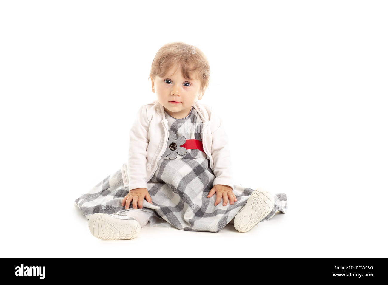 Girl élégante 1 ans assis sur le studio-de-chaussée. Arrière-plan blanc. Notion de bonheur. Banque D'Images