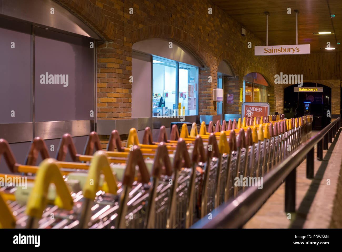 Supermarché Sainsbury's, l'entrée, les malteries Salisbury, Wiltshire, Angleterre la nuit avec des chariots de supermarché Banque D'Images