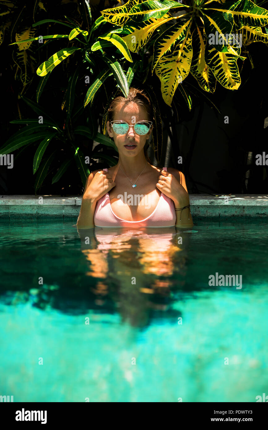 Belle jeune femme sexy en bikini rose et chapeau de paille s'amuser dans la piscine spa. Rester dans l'ombre en fille chaude journée d'été de l'hôtel Tropic island, rela Banque D'Images
