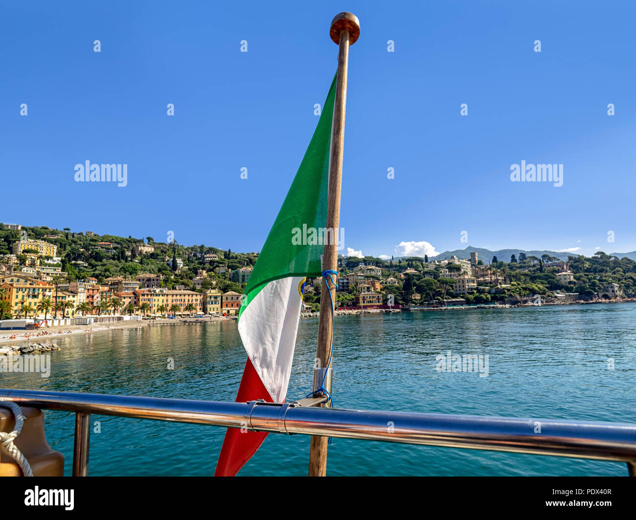 Drapeau italien à l'arrière d'un bateau avec la côte méditerranéenne pour une utilisation en arrière-plan Banque D'Images