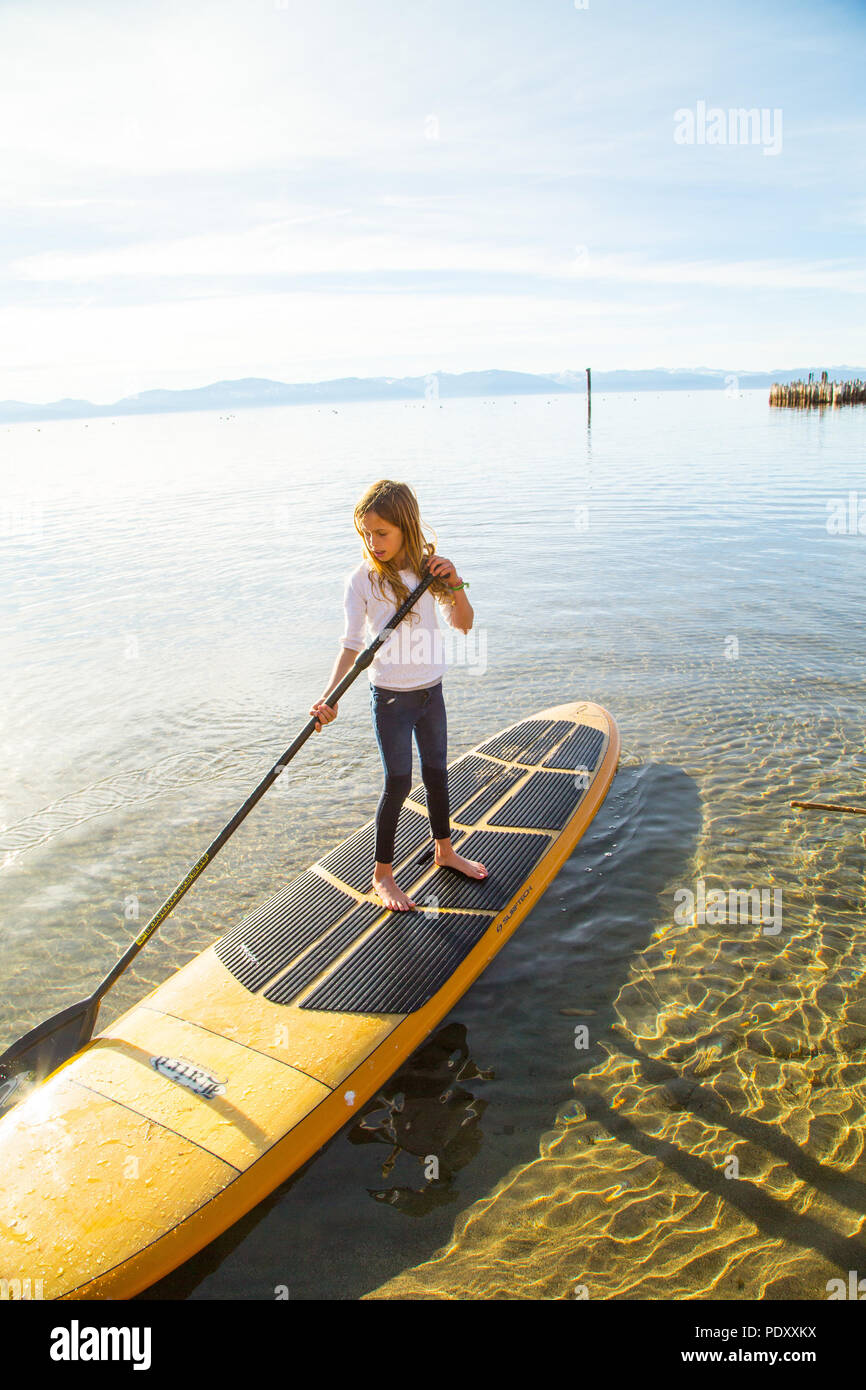 Young Girl standing on Paddle Board en eau peu profonde, le lac Tahoe, Nevada, USA Banque D'Images