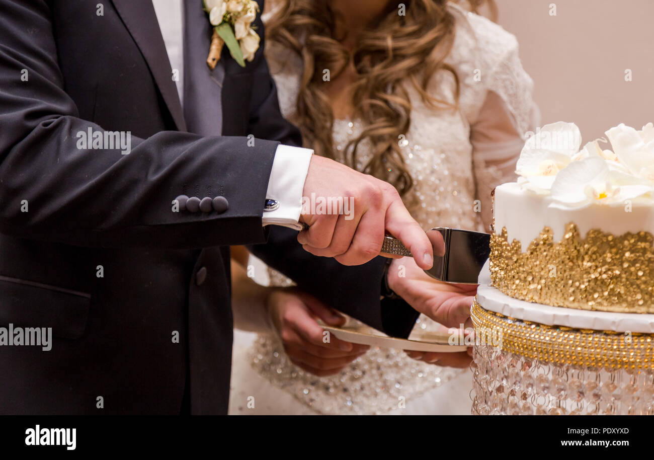 Close-up of a young woman's hands cutting leur gâteau de mariage. Banque D'Images