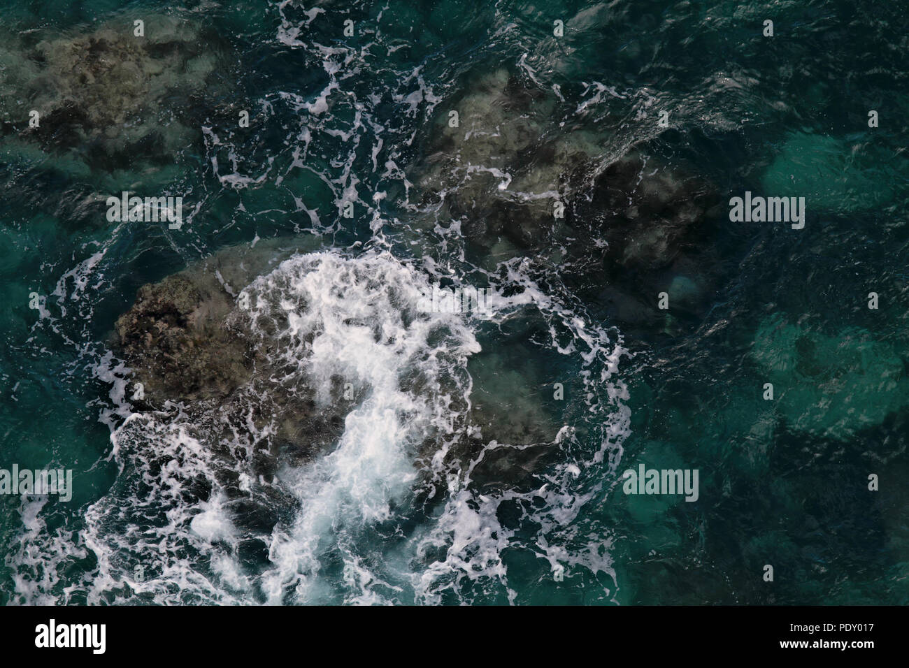 Les roches volcaniques aux vagues sur mer Banque D'Images