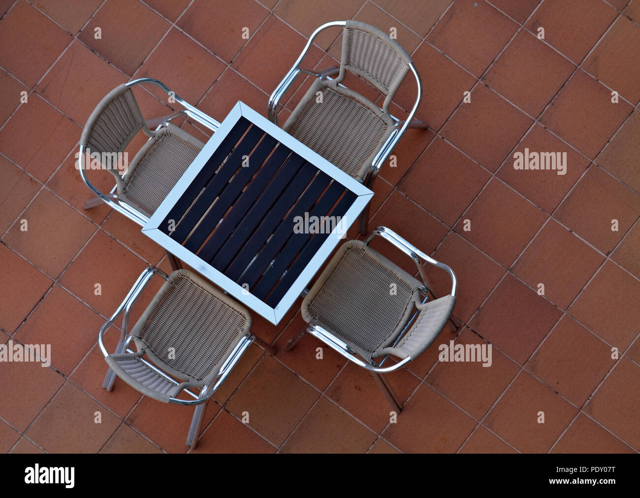 Quatre chaises de rotin autour d'une table sur la chaussée carreaux marron Banque D'Images