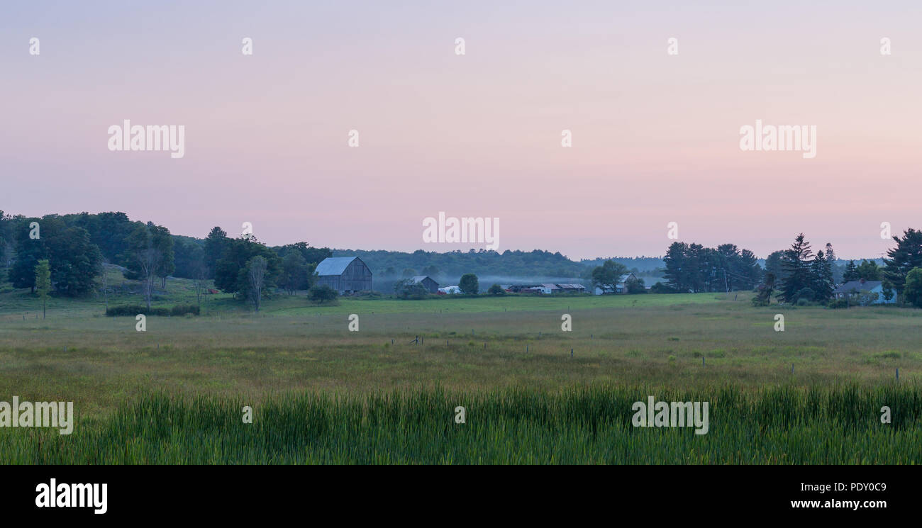 Ferme à côté d'un champ d'herbe juste après le coucher du soleil. Banque D'Images