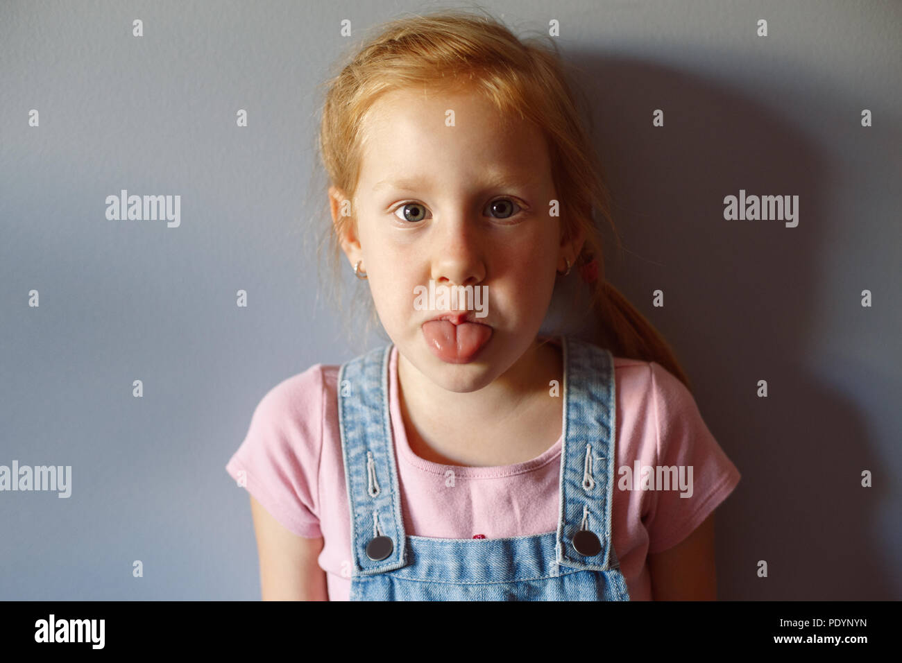Closeup portrait of cute adorable drôle de roux blanc Caucasian preschool girl à la caméra en montrant la langue. Sourire de l'enfant de s'amuser. Banque D'Images