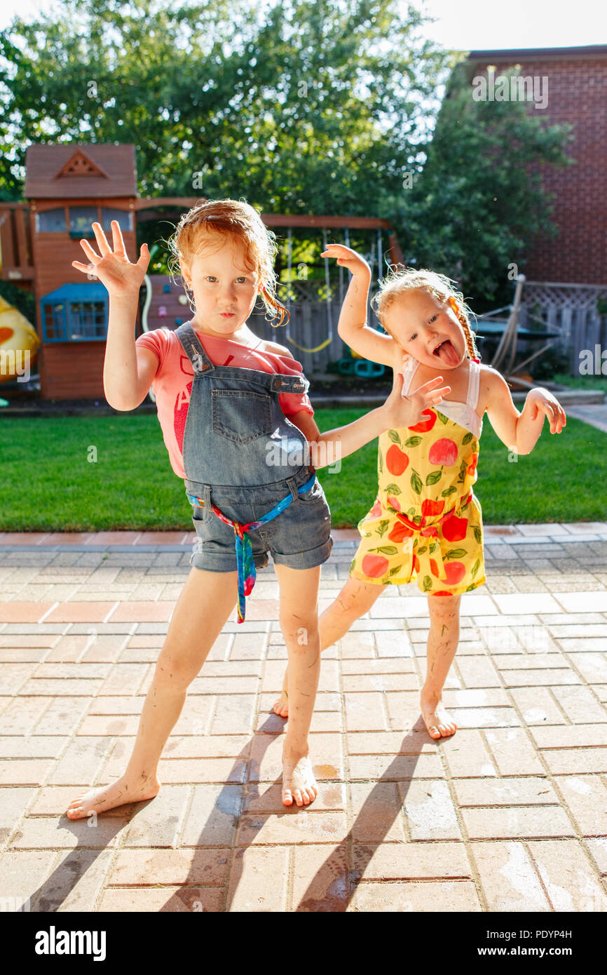 Portrait de deux petites filles, sœurs s'amusant sur l'arrière-cour d'accueil. Des visages amis filles stupides. Famille moment de vie bien positionné en couverture siblings playing Banque D'Images