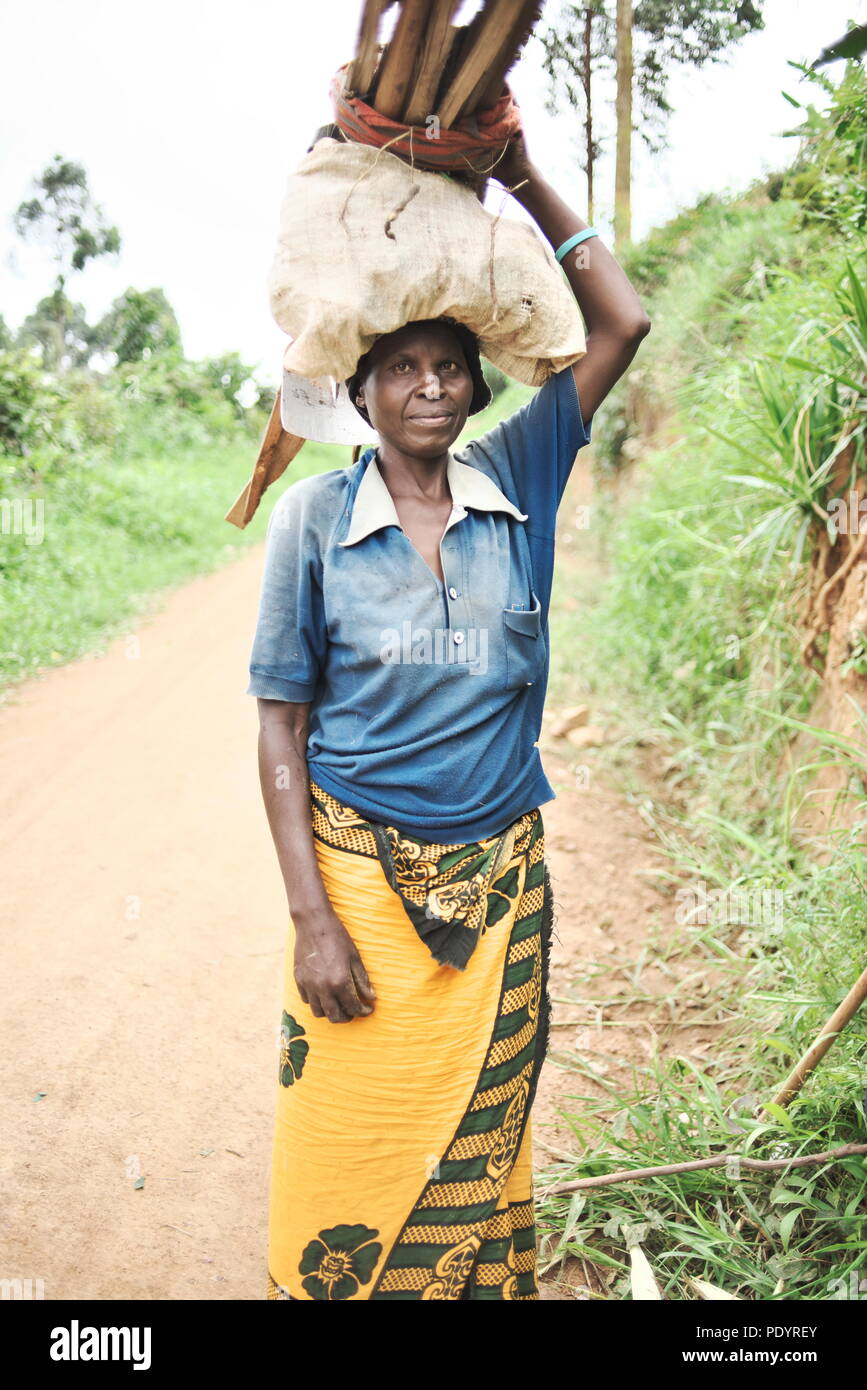 Femme ougandaise transportant des paquets de bois sur sa tête, smiling at camera Banque D'Images