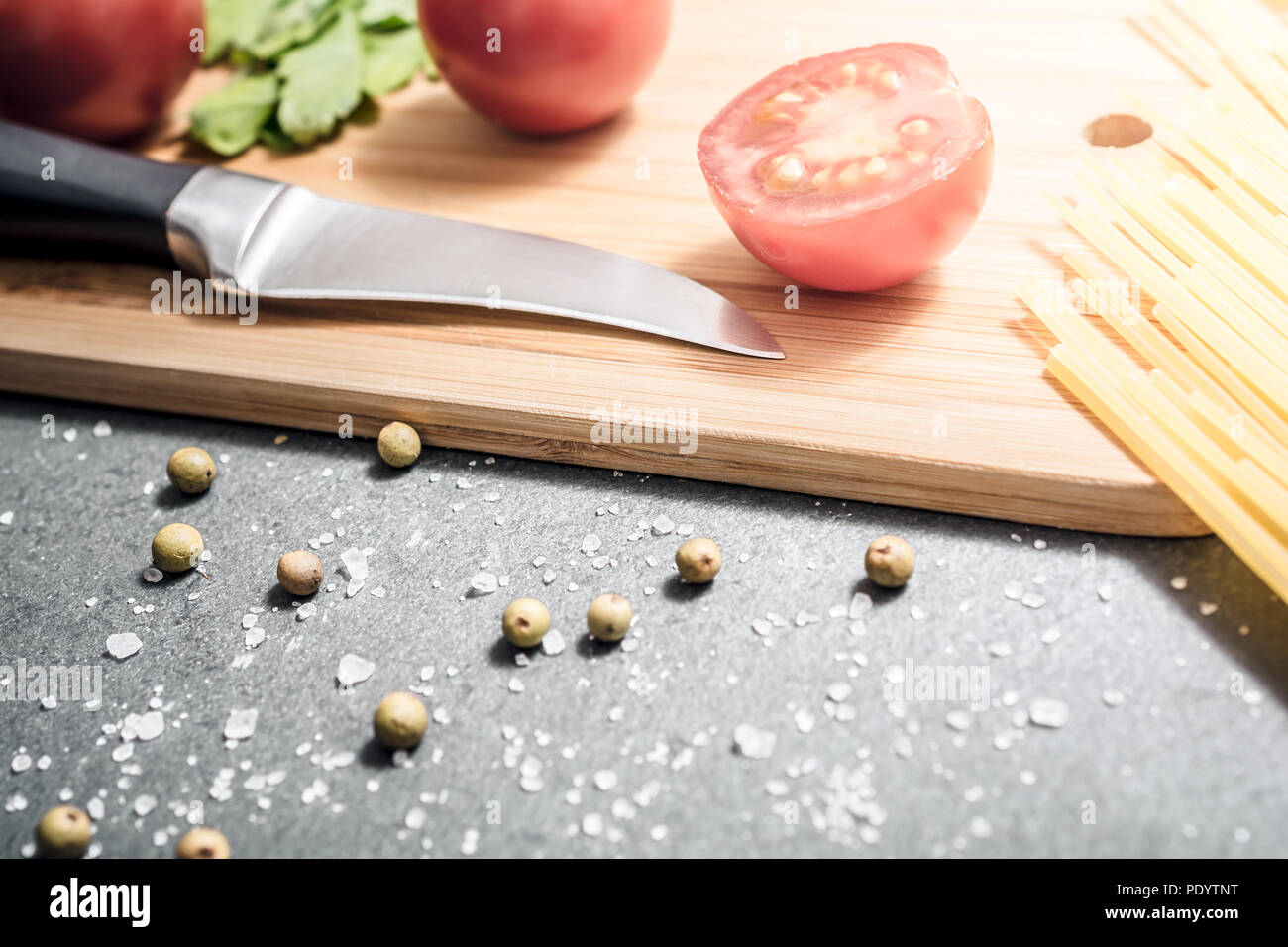Sur un couteau à découper avec une cuisine des ingrédients comme les tomates, le sel et le poivre - préparer le dîner Concept Banque D'Images