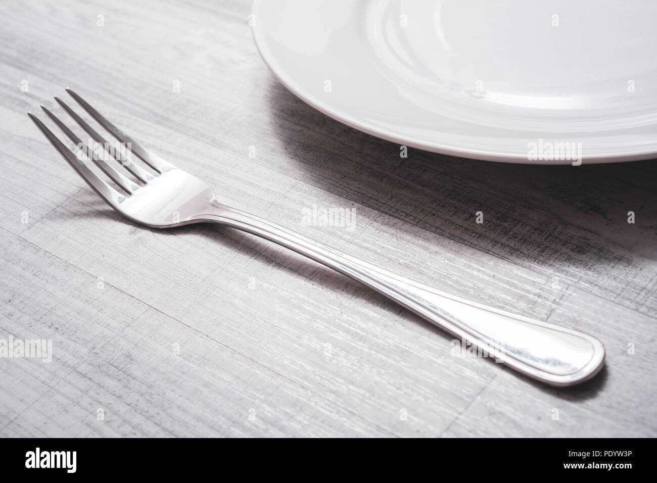 Fourche en acier inoxydable sur une table à côté d'une assiette - préparer le dîner Concept Banque D'Images