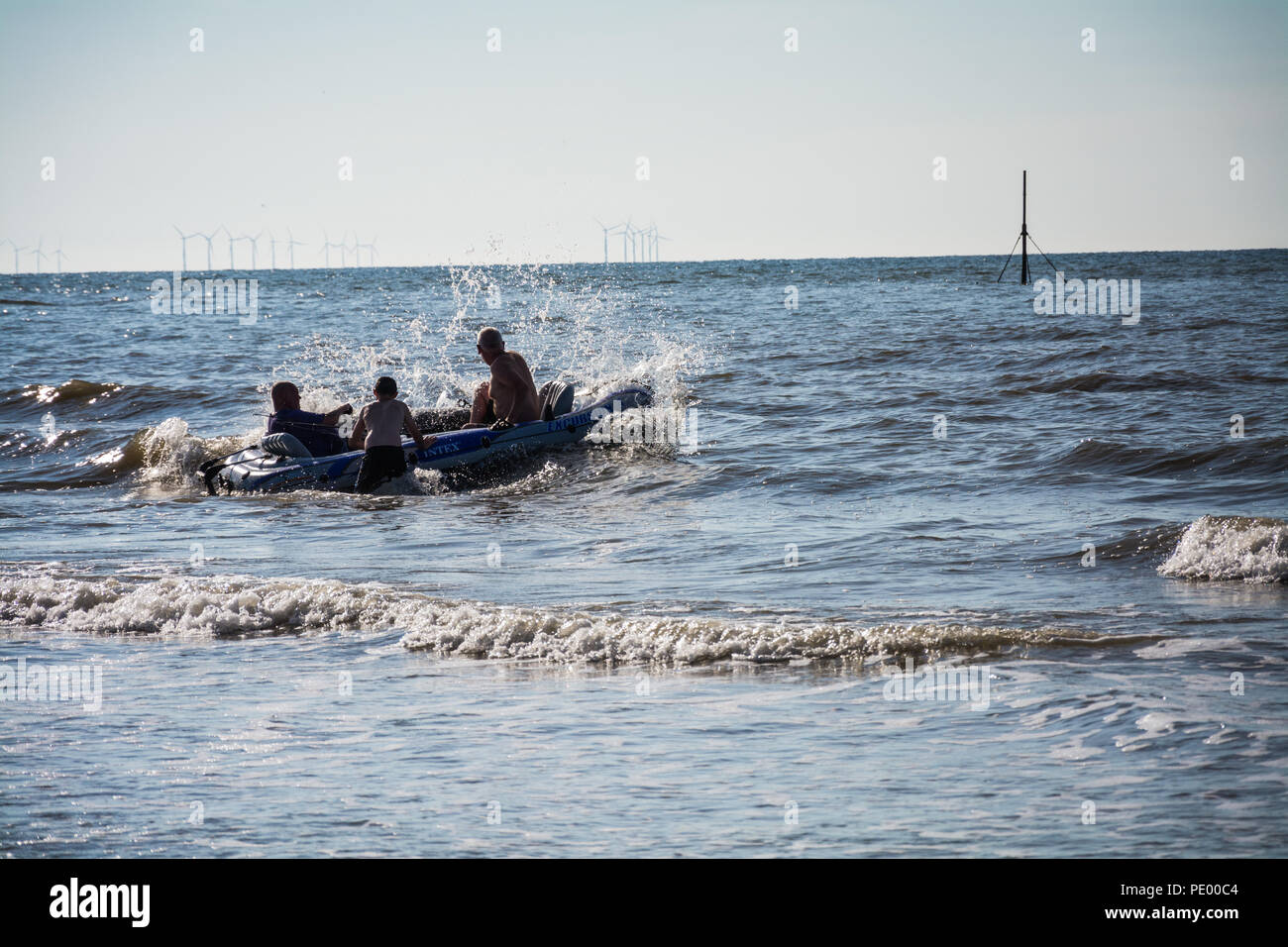 Les touristes sur un canot pneumatique jouant dans la mer au cours de l'été de canicule 2018. Plage centrale de Prestatyn, Nord du Pays de Galles, Royaume-Uni. Banque D'Images