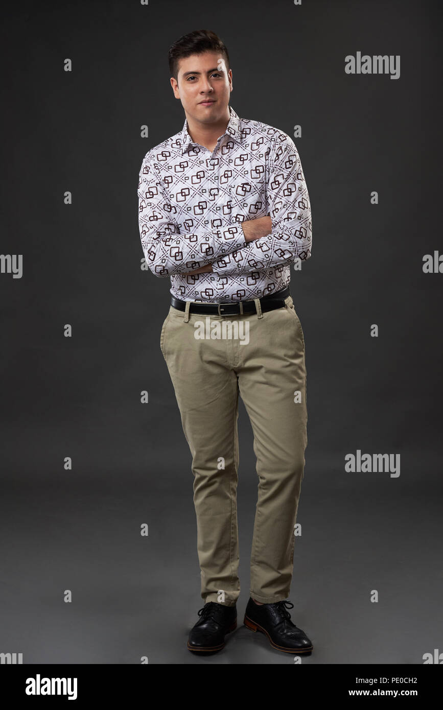 Homme debout les bras croisés en pleine longueur sur fond gris studio Banque D'Images