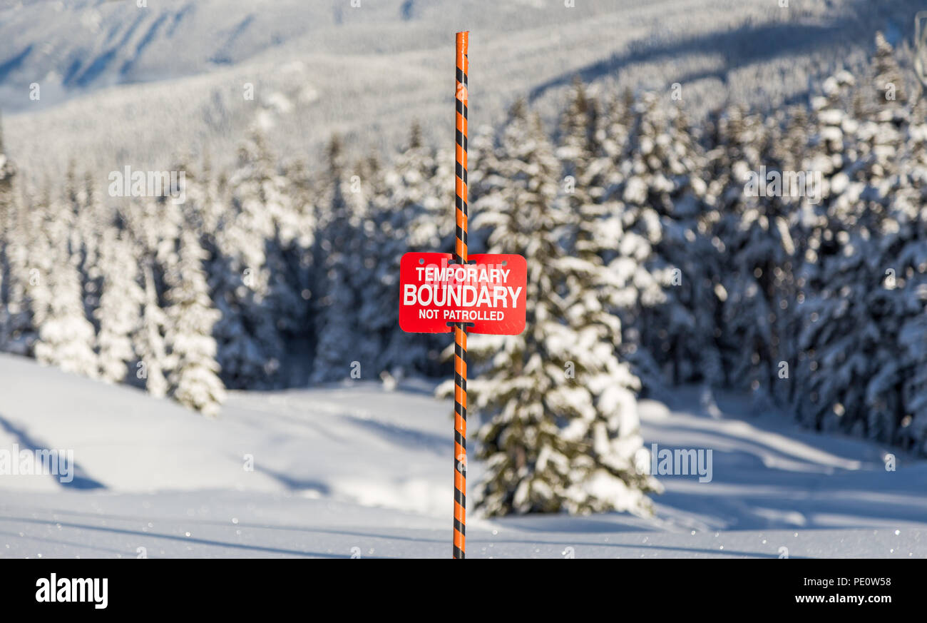 Traces dans la neige à côté d'un signe des limites de la zone de ski. Banque D'Images