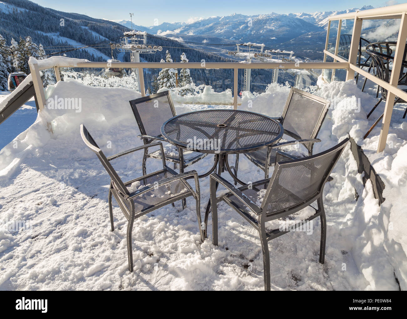 Des chaises sur un pont couvert de neige avec un télésiège tower en arrière-plan. Banque D'Images