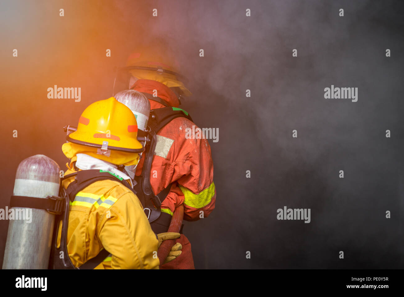 Deux pompiers de l'eau pulvérisée par la haute pression à la buse de fumée et d'incendie avec surround copy space Banque D'Images