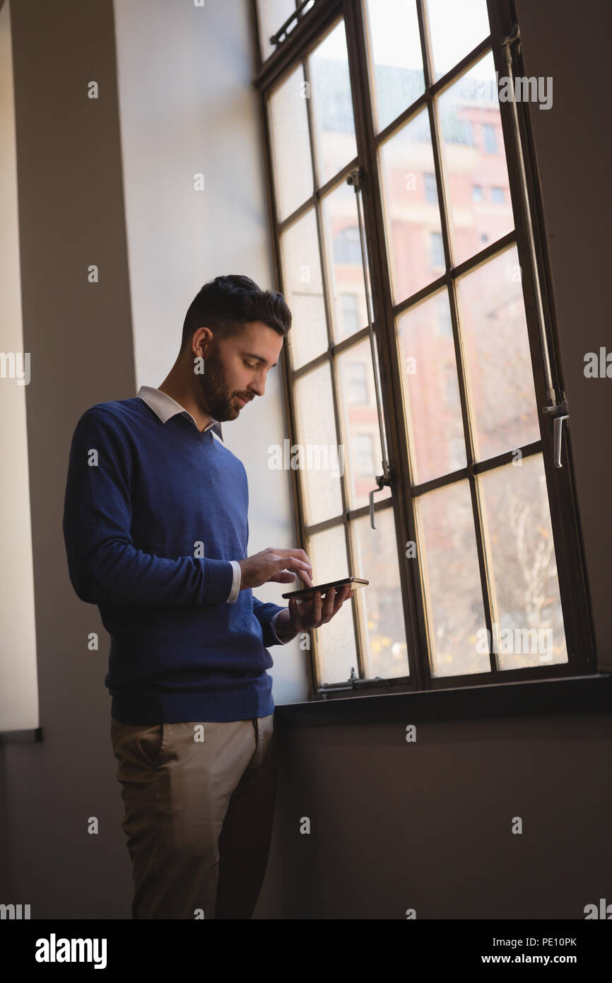 Businessman using mobile phone near window Banque D'Images