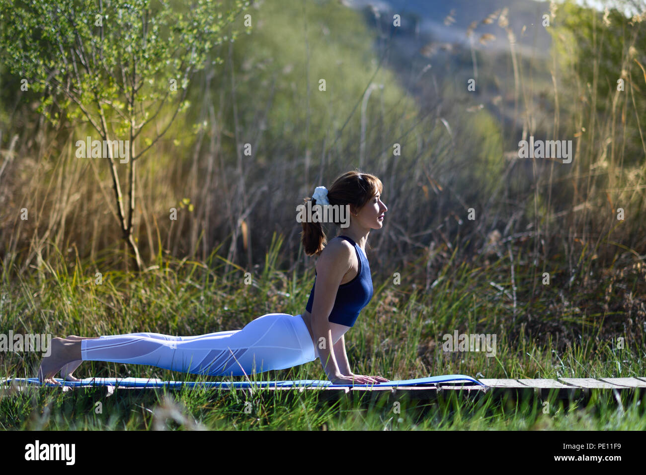 Young woman doing yoga dans la nature. Femme portant des vêtements de sport. Banque D'Images