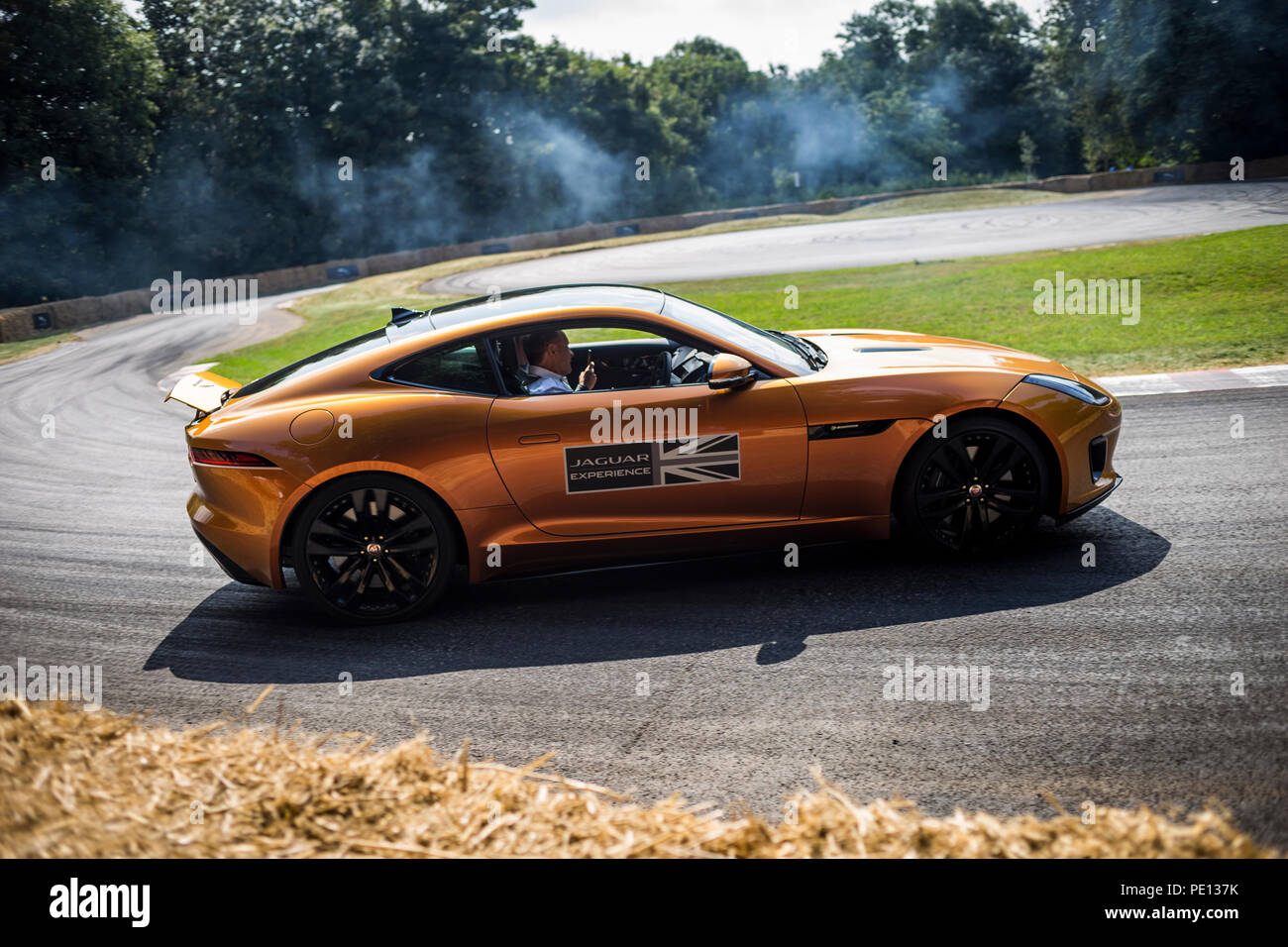 Un Jaguar sportscar tourne ses pneus, créant de la fumée, sur une piste à la Goodwood Festival of Speed 2018. Banque D'Images