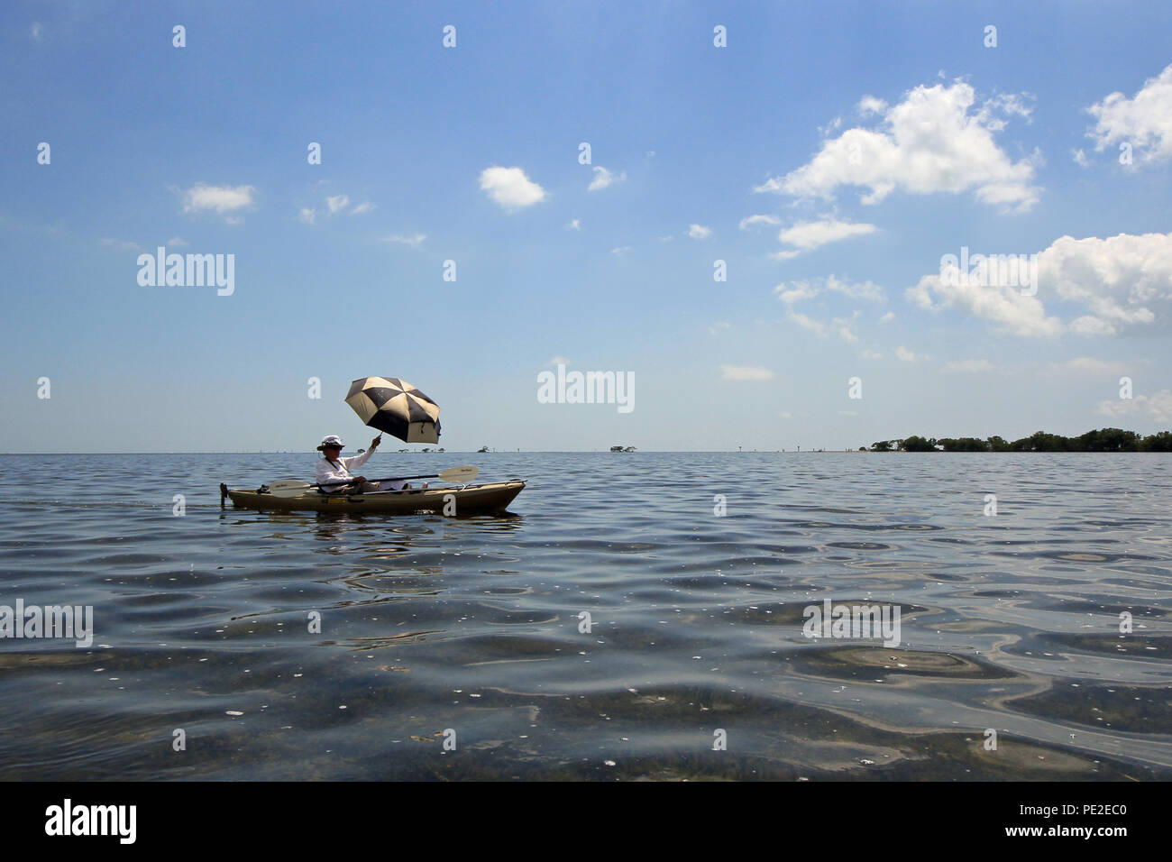Senior en utilisant un parapluie comme une voile tout en kayak dans la baie Biscayne au large de Point noir, au sud de Miami, Floride. Banque D'Images