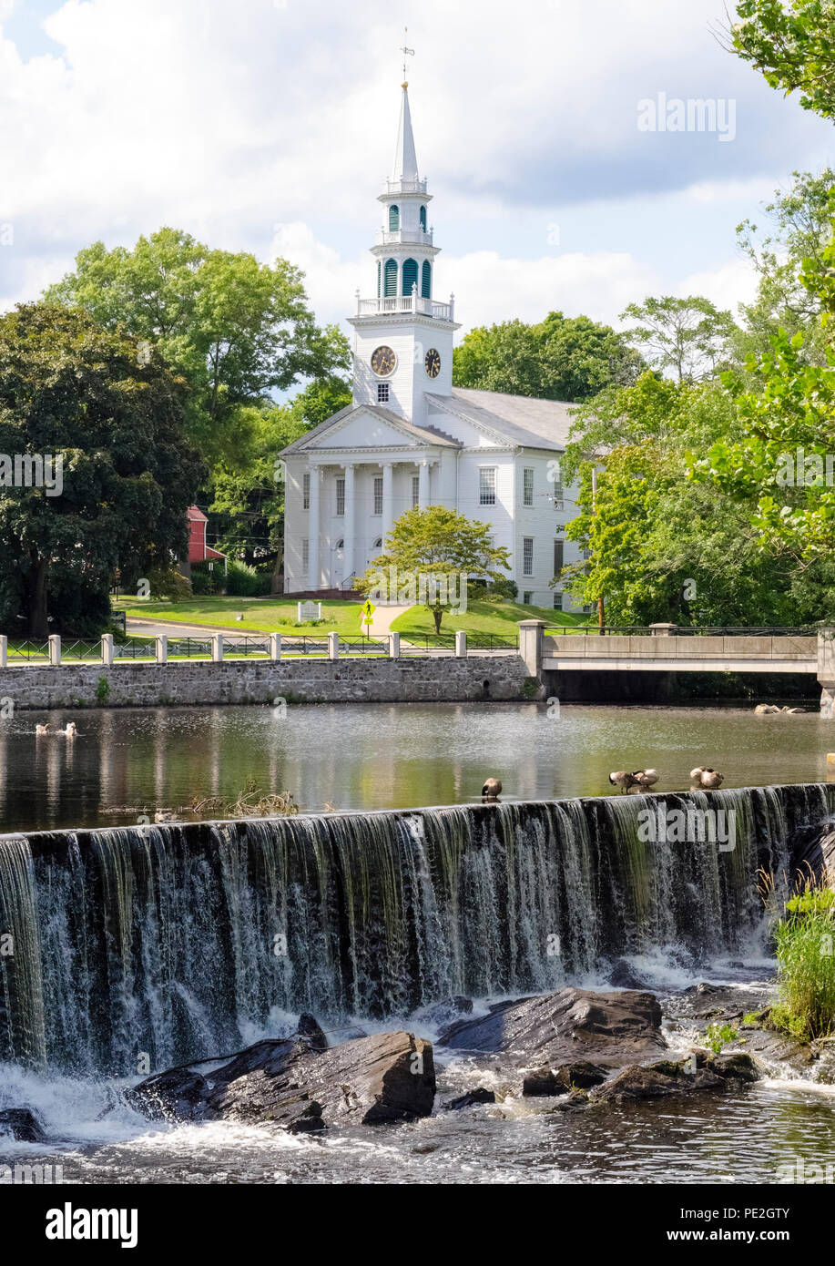 Le livre blanc-columned Première Église unie du Christ avec l'horloge et son clocher date de 1824 et donne sur un lagon dans ce pittoresque scène de la Nouvelle-Angleterre dans le cœur historique de la Milford, Connecticut, USA. Maintenant pour s'identifier comme "une petite ville avec un grand Cœur, il a été fondée en 1639 comme une colonie anglaise appelé Wepowage, le nom indien de la rivière qui coulait à travers la colonie. Un an plus tard, elle a été renommée Milford en référence à un moulin établi là. Banque D'Images